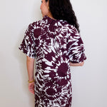 Woman wearing a patterned dress against a white wall