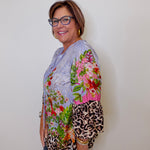 Woman wearing a colorful floral and leopard print top against a plain background