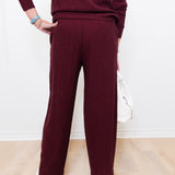 Person wearing a burgundy sweater and pants on a light wooden floor.