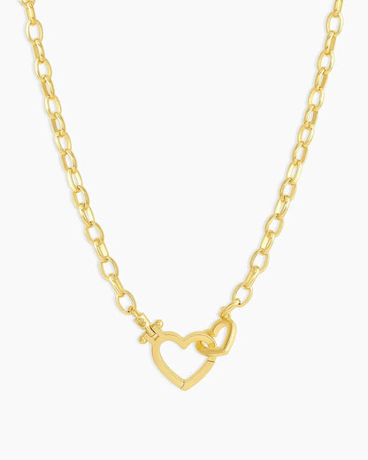Gold necklace with a heart-shaped clasp on a white background
