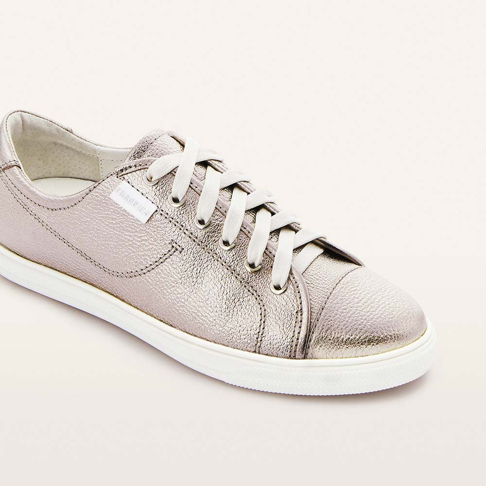 Silver sneaker with white laces on a light gray background