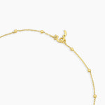 Gold bracelet with a heart charm on a white background