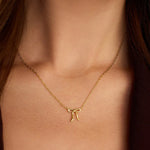 Gold necklace with a bow pendant on a person's neck