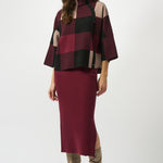 Woman wearing a burgundy and black checkered top with a matching skirt on a white background