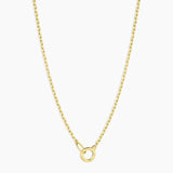 Gold necklace with a small round pendant on a white background