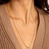 Gold necklace worn by a person in a brown sweater