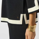 Black outfit with white trim and gold cuff on a plain background
