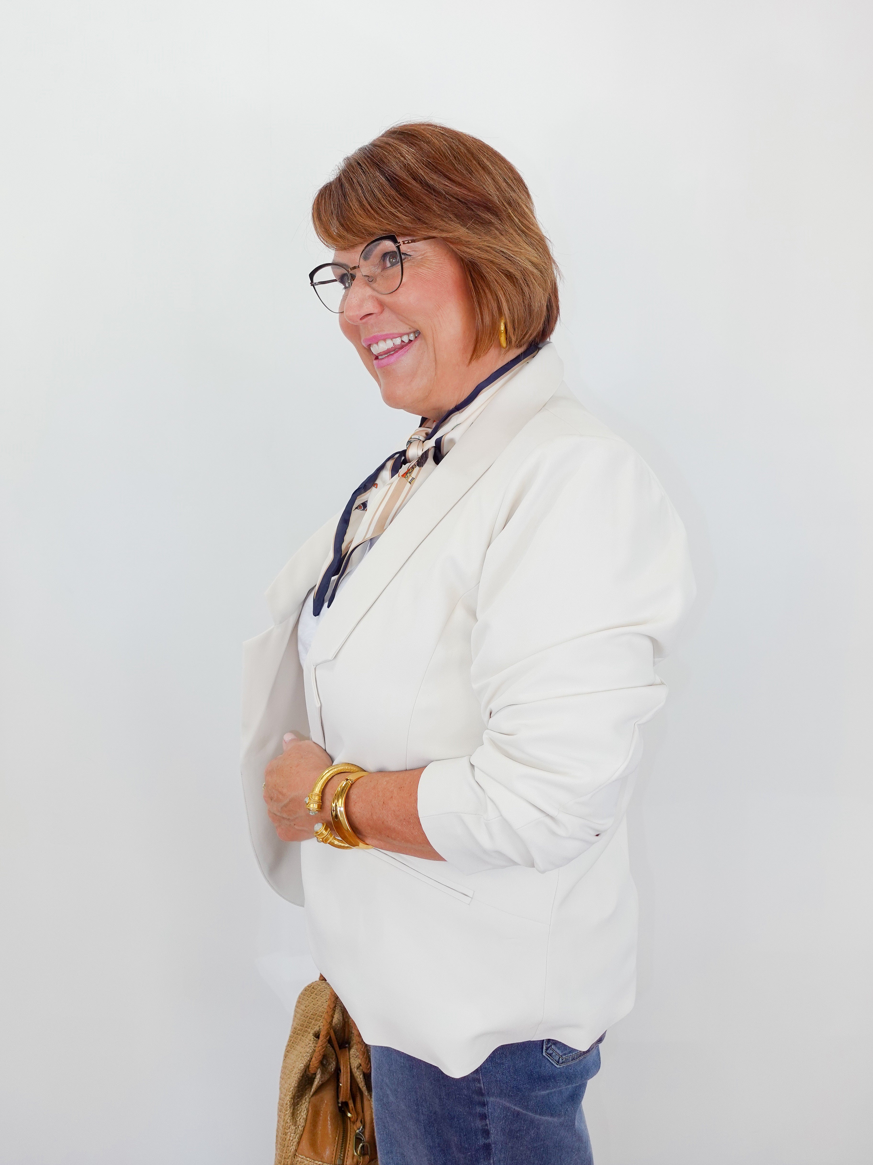 Woman wearing a white blazer and glasses against a white background