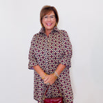 Woman wearing a patterned dress with a red handbag against a white background