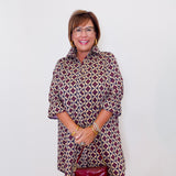 Woman wearing a patterned dress with a red handbag against a white background