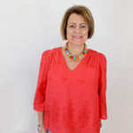 Woman wearing a red blouse with lace details against a white background