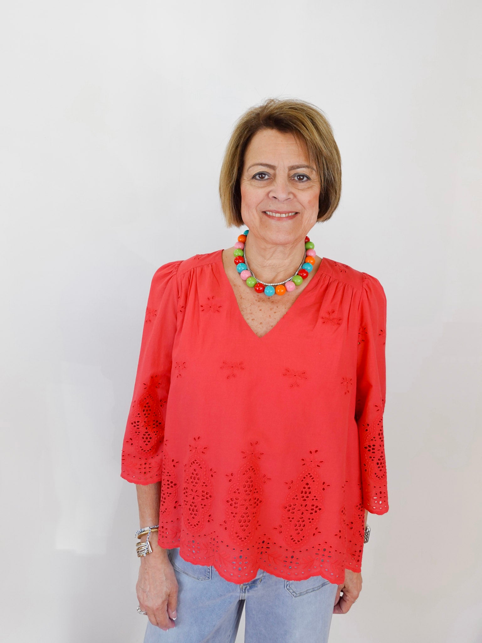 Woman wearing a red blouse with lace details against a white background