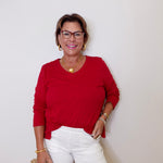Woman wearing a red top and white shorts against a plain background