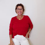 Woman wearing a red top and white shorts against a plain background