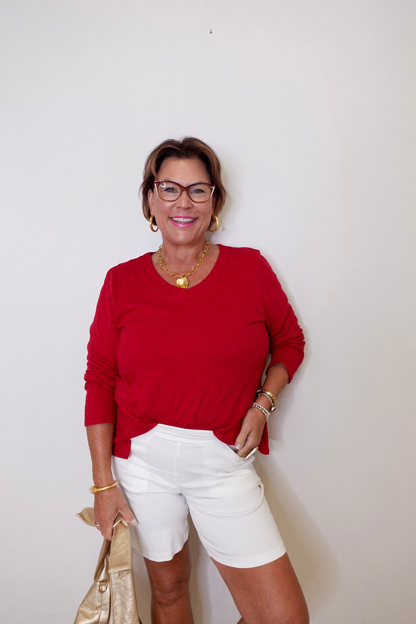 Woman wearing a red top and white shorts against a plain background