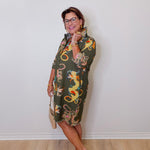 Woman wearing a patterned dress standing against a plain white wall.