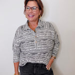Woman wearing a patterned shirt and glasses against a plain background