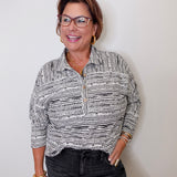 Woman wearing a patterned shirt and glasses against a plain background