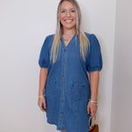 Woman wearing a blue denim dress against a white wall