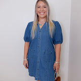 Woman wearing a blue denim dress against a white wall