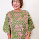 Woman wearing a green and pink patterned blouse against a white background
