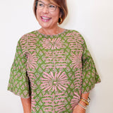 Woman wearing a green and pink patterned blouse against a white background