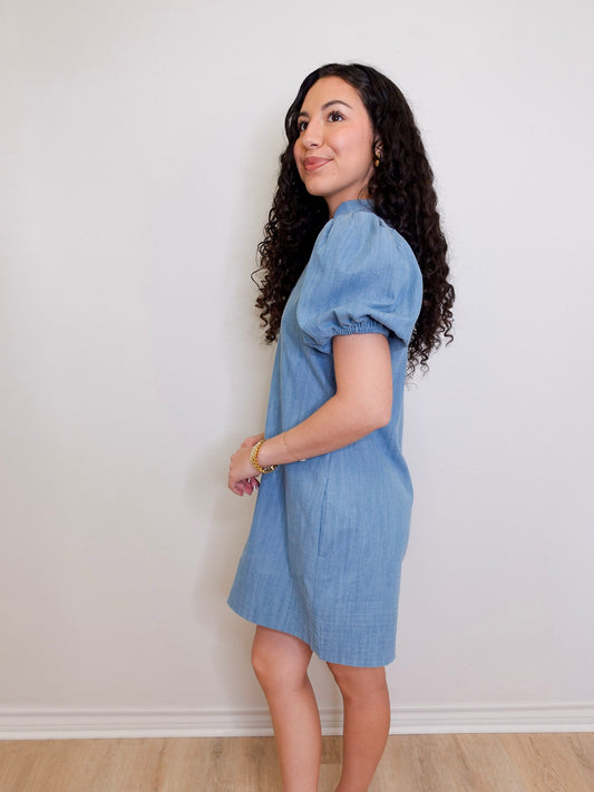 Woman wearing a blue dress against a white wall