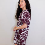 Woman wearing a patterned dress against a white wall