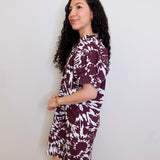Woman wearing a patterned dress against a white wall