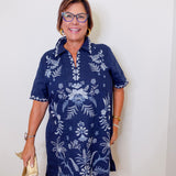 Woman wearing a navy blue dress with white floral patterns against a white background
