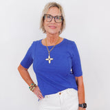 Woman wearing a blue shirt and white pants against a white background