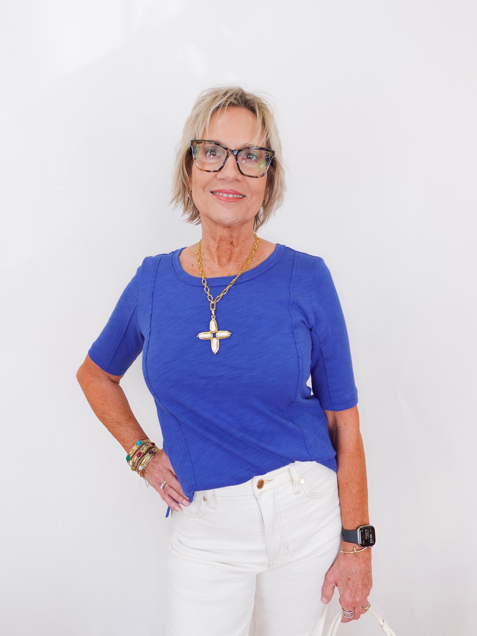 Woman wearing a blue shirt and white pants against a white background