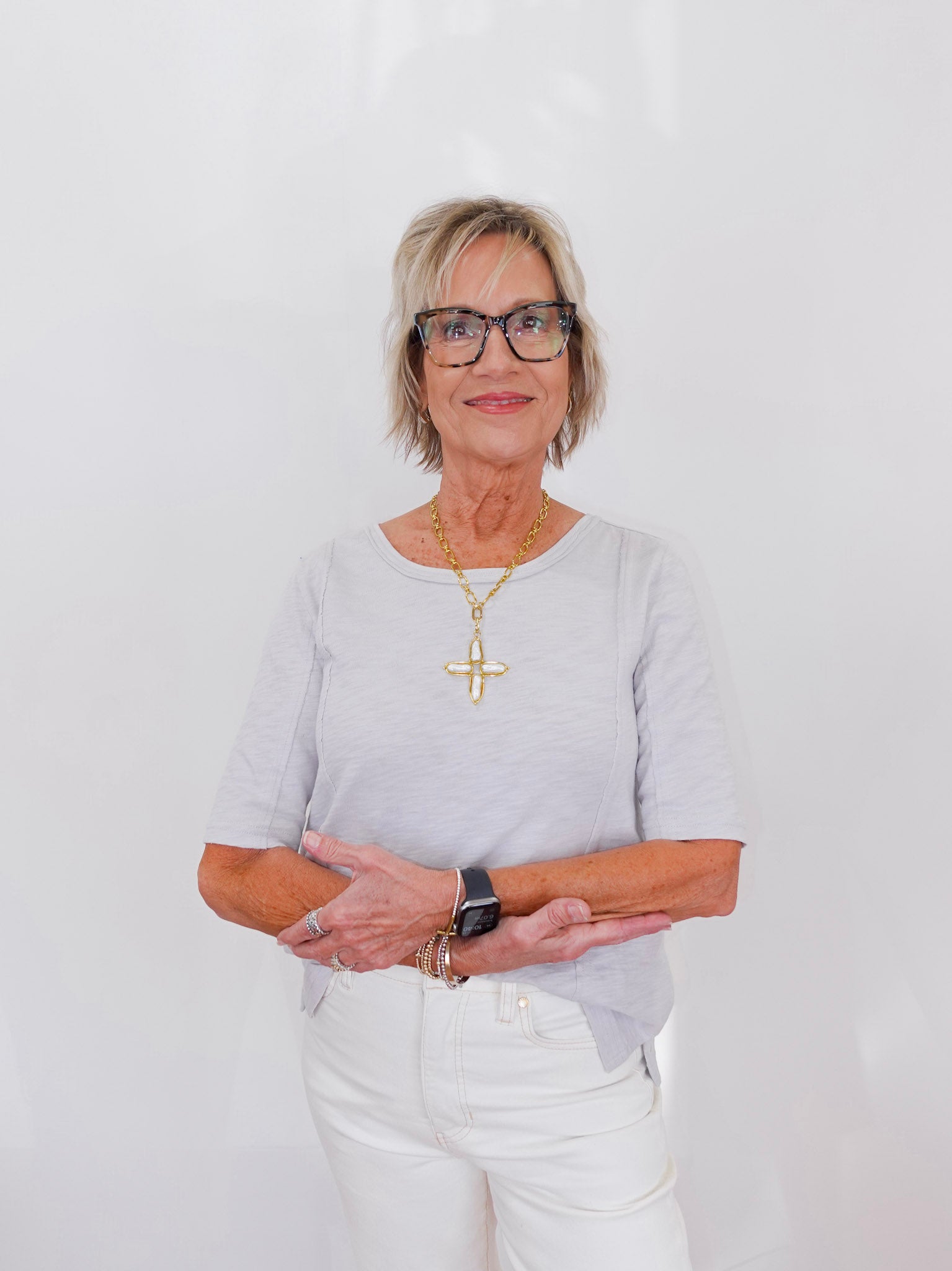 Woman wearing glasses and a light gray shirt with a white background