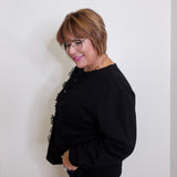 Woman wearing a black outfit with floral details against a plain background
