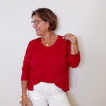 Woman wearing a red top and white shorts against a plain background