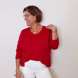 Woman wearing a red top and white shorts against a plain background