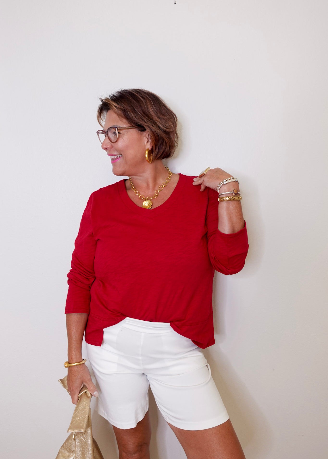 Woman wearing a red top and white shorts against a plain background