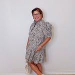 Woman wearing a patterned dress against a white wall