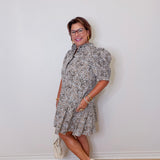 Woman wearing a patterned dress against a white wall
