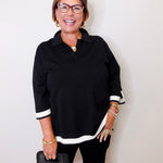 Woman wearing a black outfit with white accents against a white background