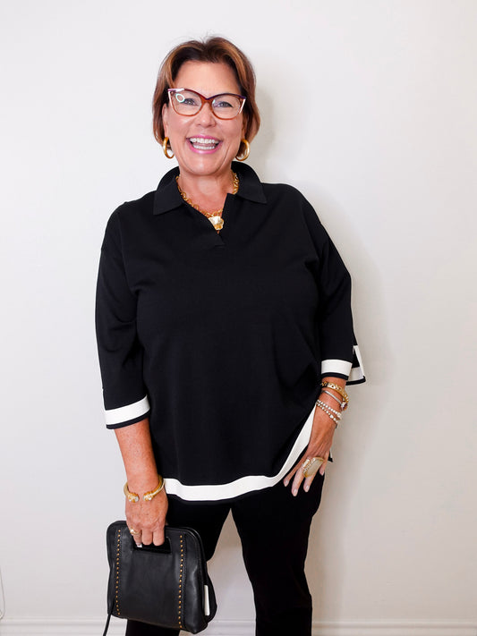 Woman wearing a black outfit with white accents against a white background