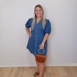Woman wearing a blue dress standing against a white wall.