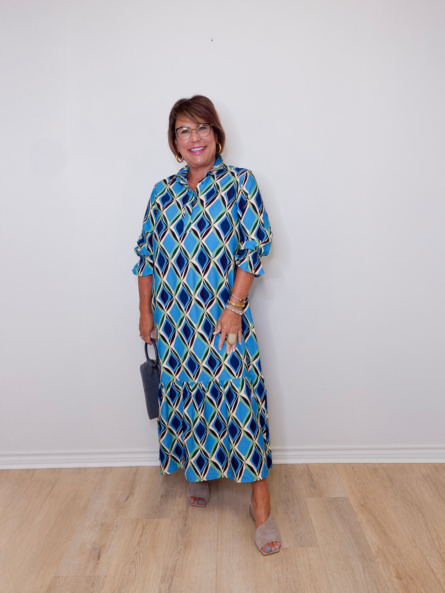 Woman wearing a blue patterned dress against a white wall