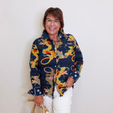 Woman wearing a colorful dragon-patterned jacket against a white background
