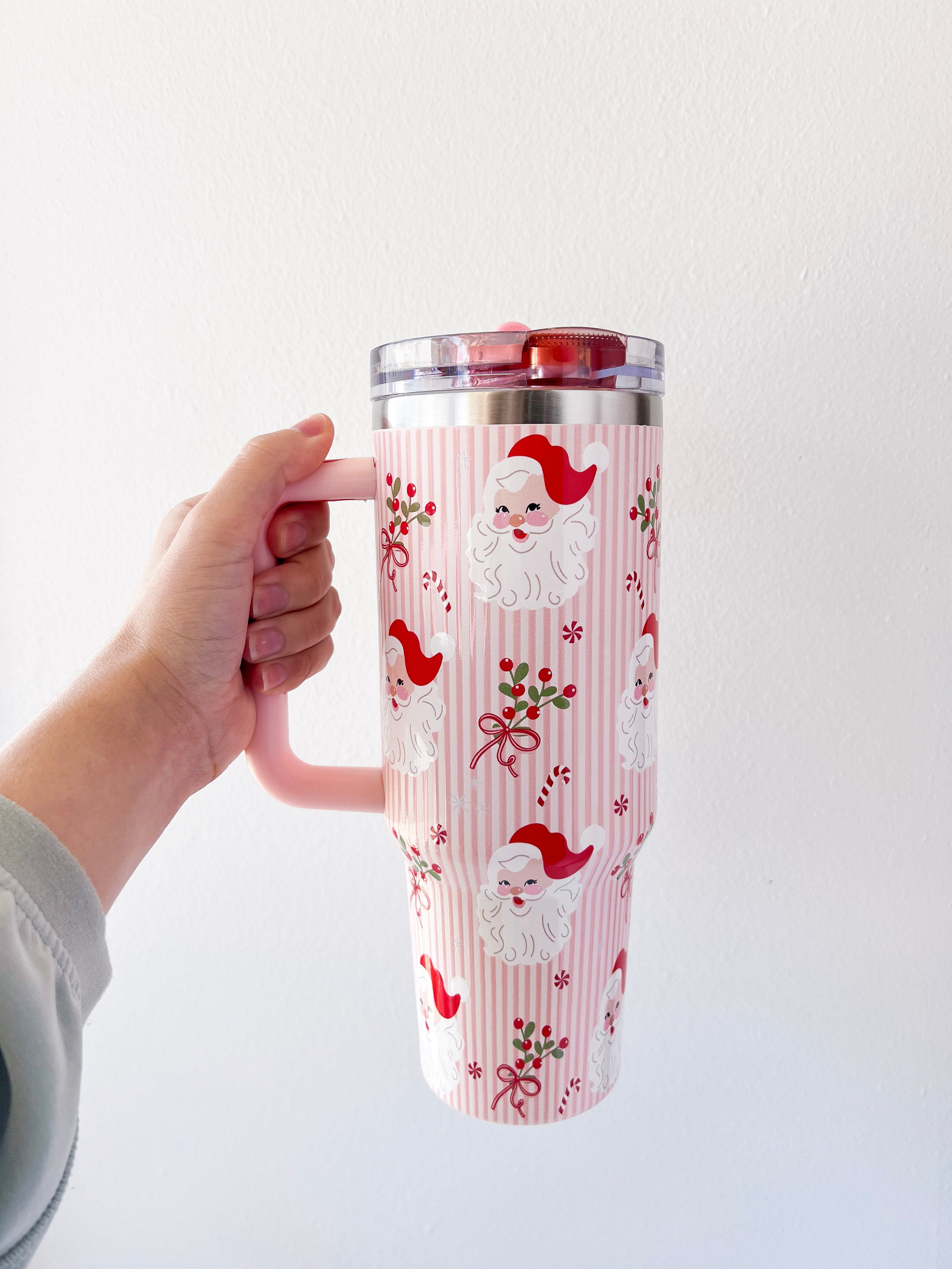 Tumbler with Santa Claus design held by a hand against a white background