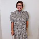 Woman wearing a patterned dress against a white wall