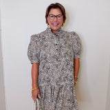 Woman wearing a patterned dress against a white wall