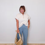 Woman holding a gold handbag against a white wall