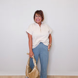 Woman holding a gold handbag against a white wall