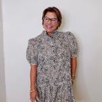 Woman wearing a patterned dress against a white wall